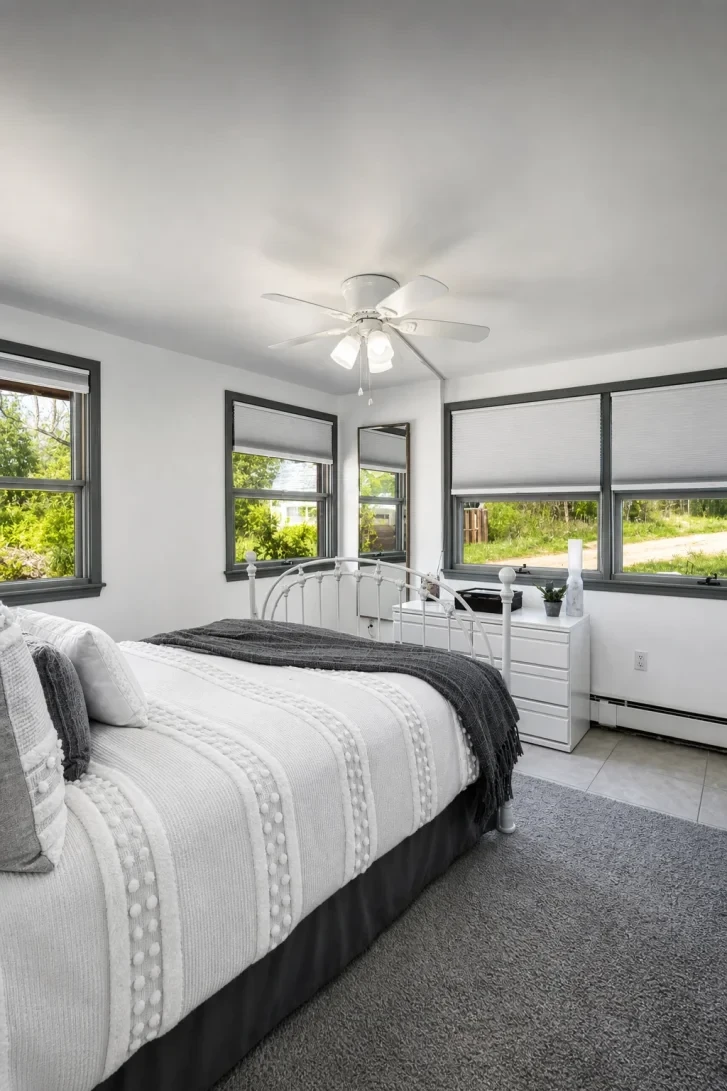 Dark-Framed Windows Wrap a White Iron Bed